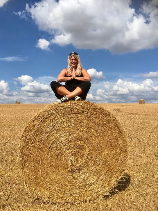 reiki for migraine reiki master sitting on straw bale in field of straw