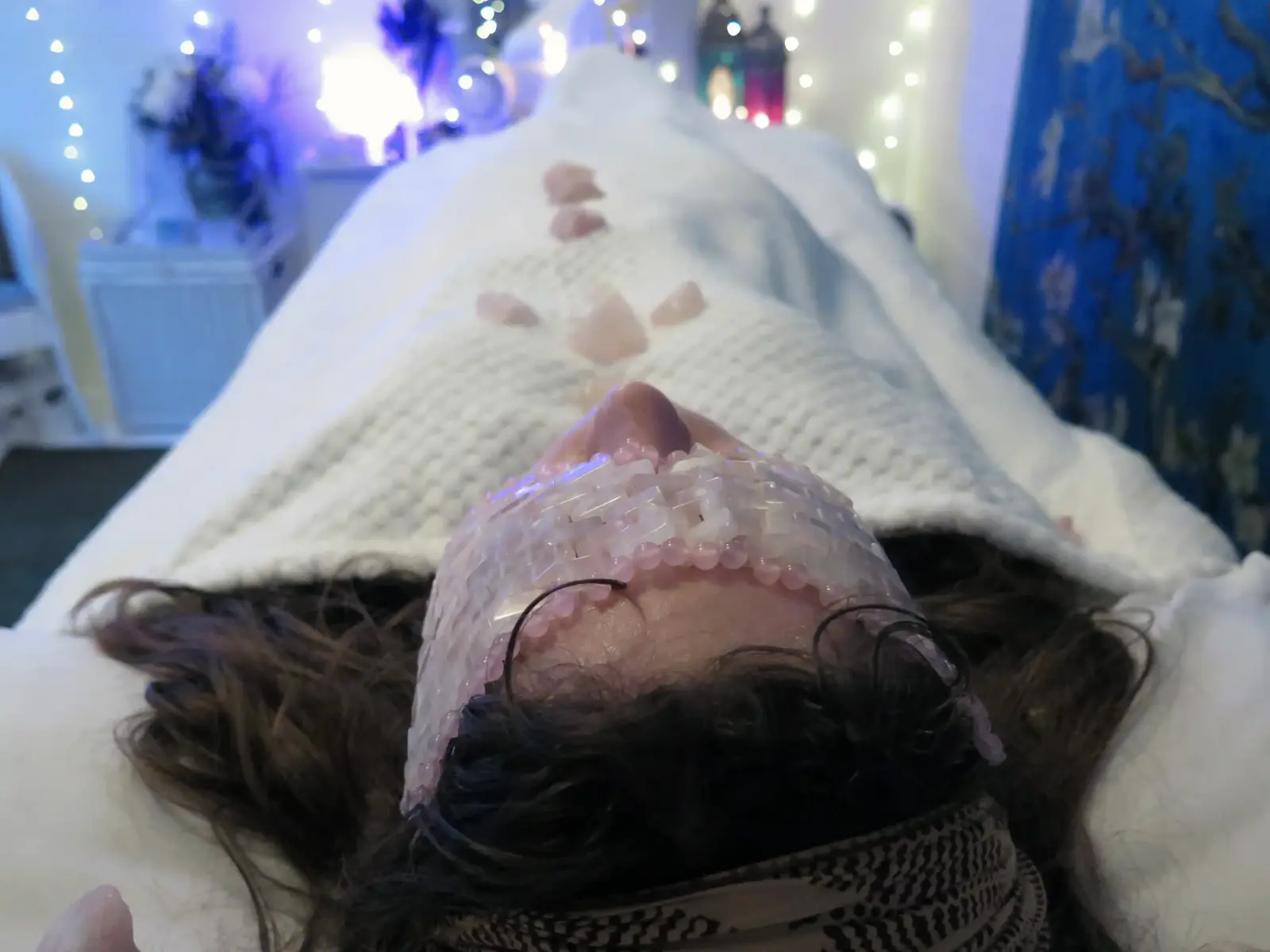 Client laying on a Reiki bed in Maidenhead with a rose quartz crystal mask on surrounded by rose quartz crystals